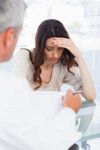 Sad woman listening to her docter talking about a illness in medical office