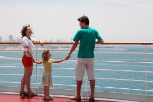 Family With Daughter Standing On Cruise Liner Deck And Holding F