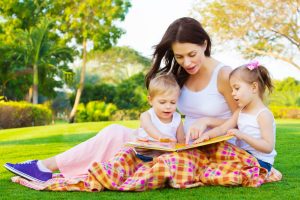 Photo of young brunette woman teaching two sweet kids, cheerful